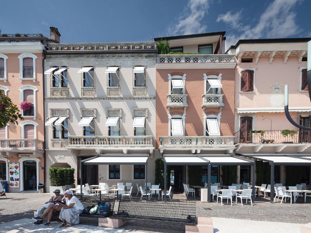 deux personnes assises sur un banc devant un bâtiment dans l'établissement Hotel Locanda del Benaco, à Salò