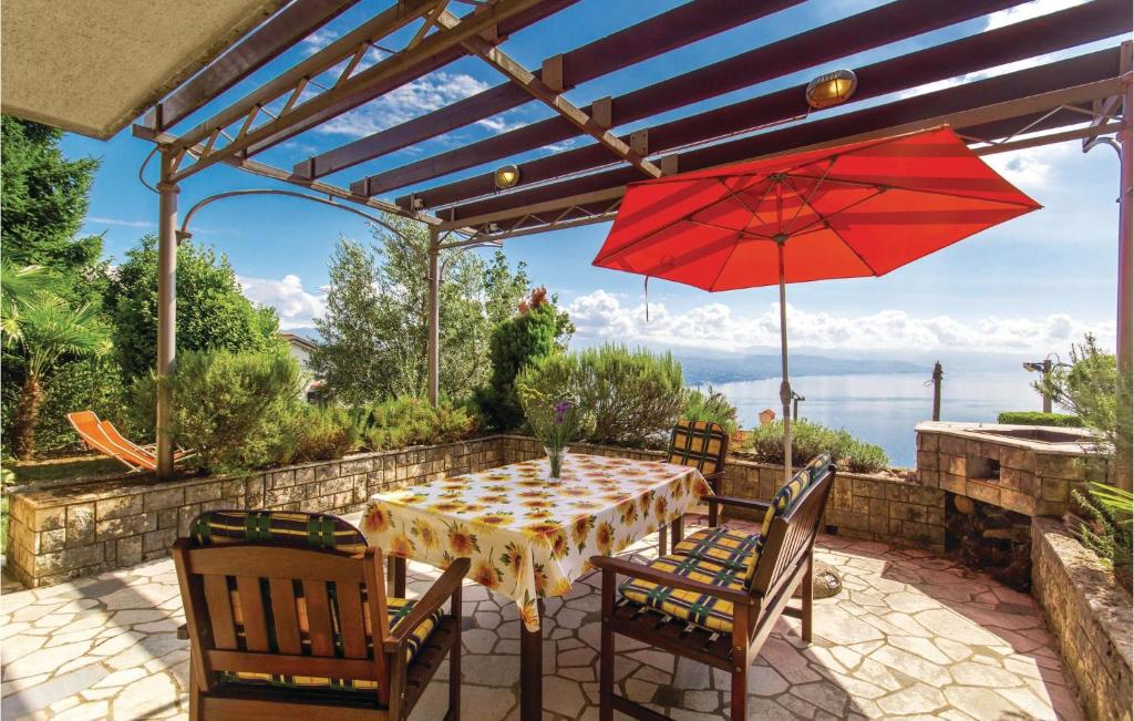 a table with a red umbrella on a patio at 2 Bedroom Pet Friendly Apartment In Kolavici in Veprinac