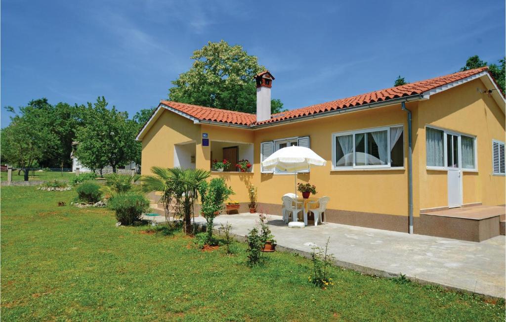 a small yellow house with a table and an umbrella at 1 Bedroom Stunning Home In Marceljani in Vinež