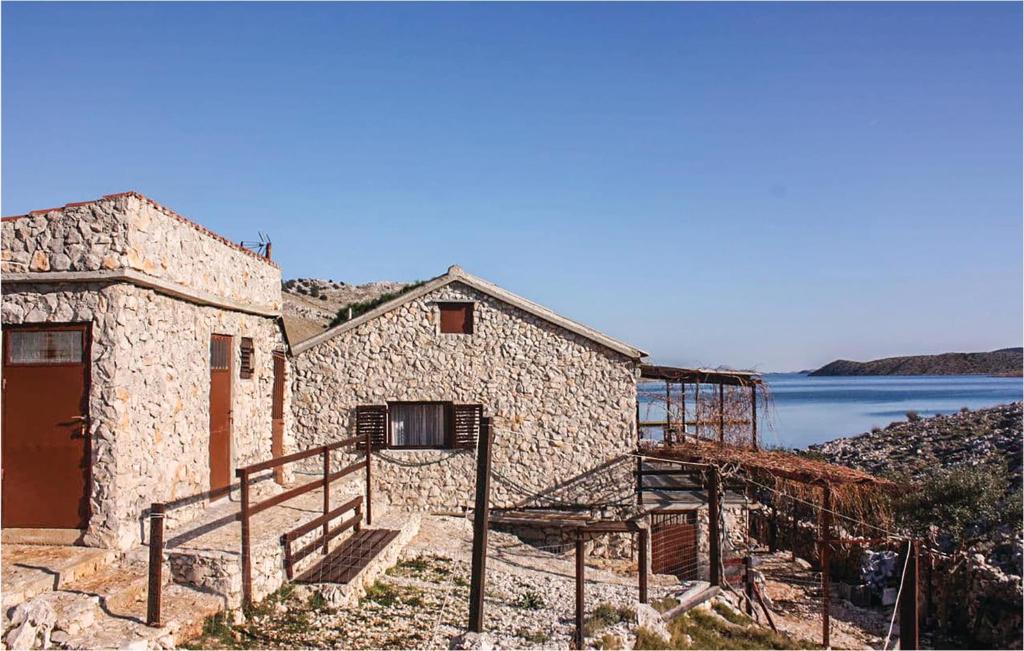 a stone building with stairs next to a body of water at Amazing Home In Kornati With House Sea View in Vrulje