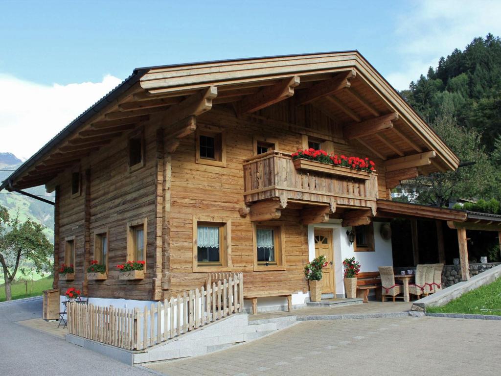 ein Holzhaus mit einem Balkon und roten Blumen in der Unterkunft Beautiful detached chalet in Mayrhofen Ramsau Tyrol with sauna in Ramsau im Zillertal