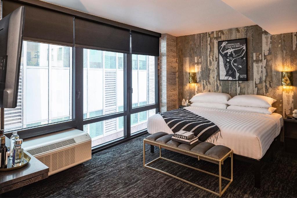 a bedroom with a large bed and large windows at The FIDI Hotel in New York