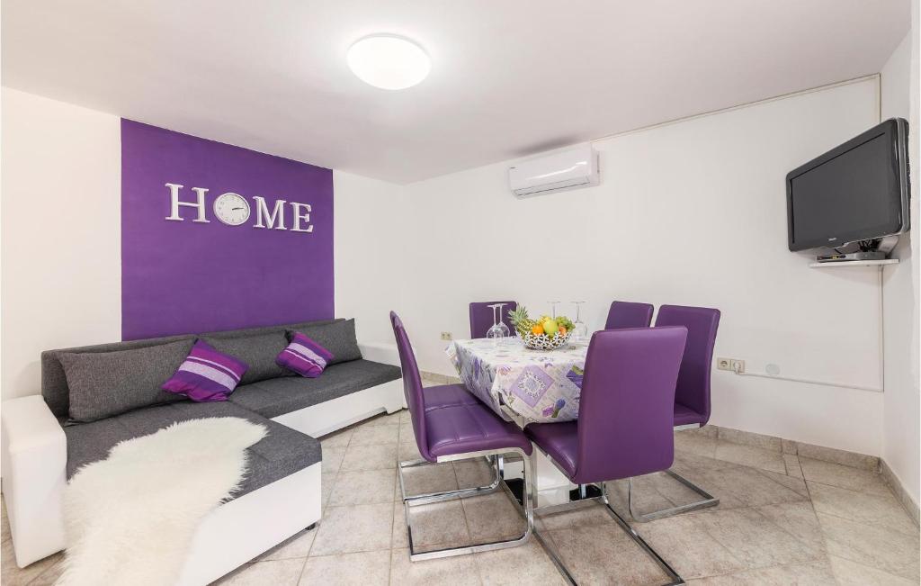 a living room with a couch and a table with purple chairs at Gorgeous Apartment In Pavicini With Kitchen in Pavicini