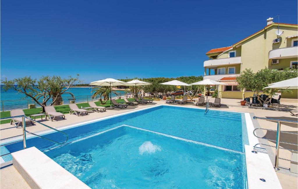 una piscina in un resort con sedie e ombrelloni di Stunning Apartment In Povljana With Outdoor Swimming Pool a Povljana (Pogliana)