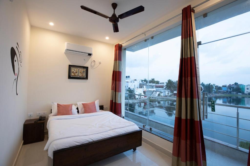 sypialnia z łóżkiem i dużym oknem w obiekcie Thiru Pavilion Retreat w mieście Mahabalipuram