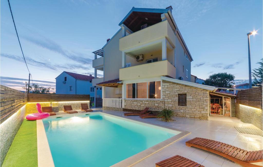 a villa with a swimming pool in front of a house at Pet Friendly Apartment In Biograd With Kitchen in Biograd na Moru