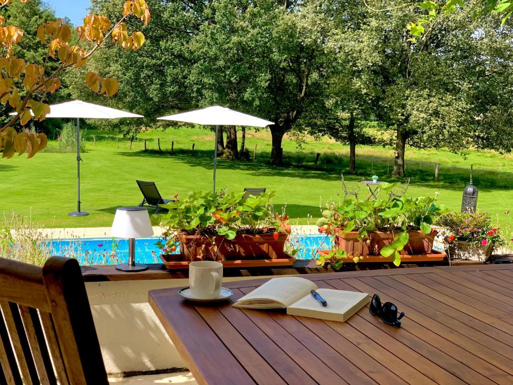 une terrasse en bois avec une table et un livre. dans l'établissement LA MAISON D INÈS and UGOLIN & Spa, à Baccarat