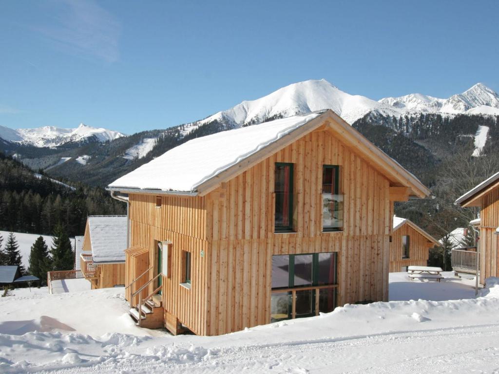 ein Holzhaus im Schnee mit Bergen im Hintergrund in der Unterkunft Chalet in Hohtauern Styria with sauna in Hohentauern