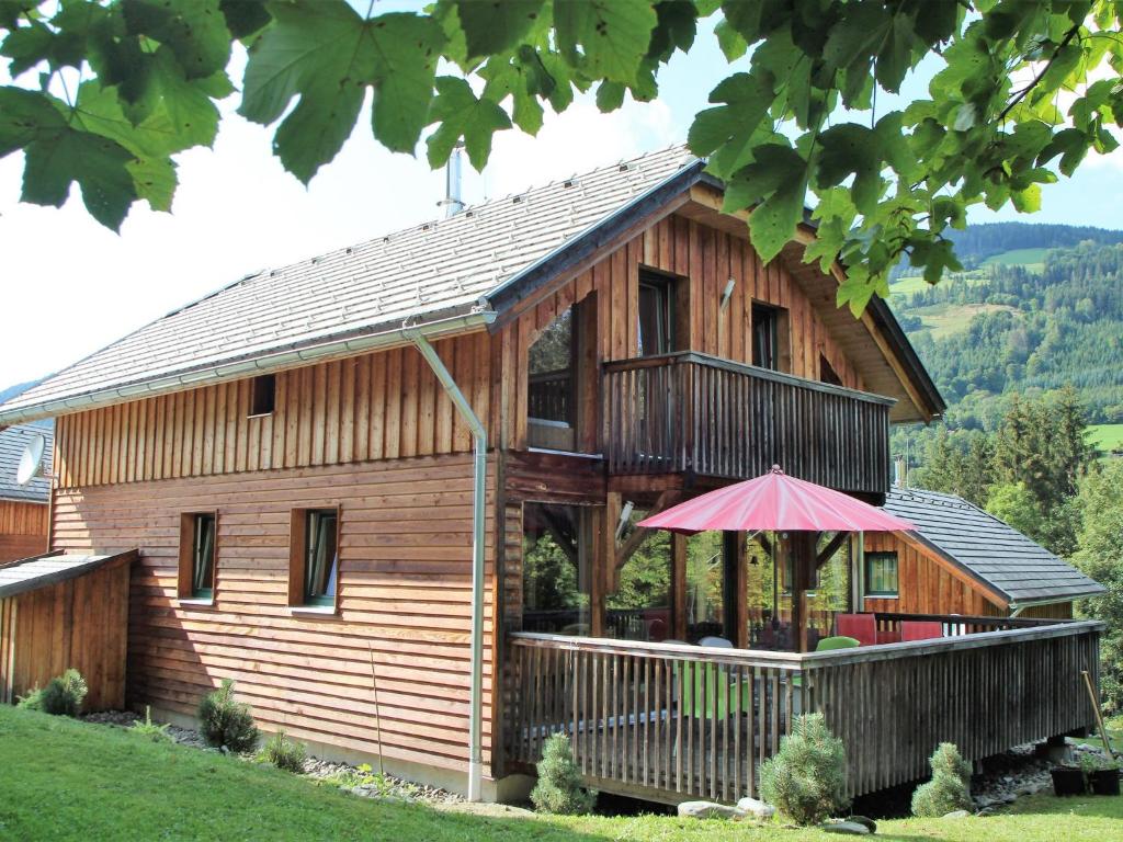 a large wooden house with a porch and an umbrella at Chalet in St Georgen ob Murau near ski area in Sankt Georgen ob Murau
