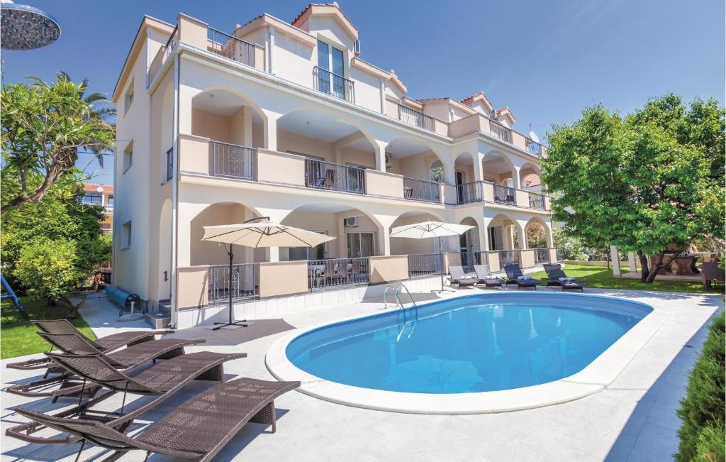 a large villa with a swimming pool and chairs at Beautiful Apartment In Kastel Stafilic With 5 Bedrooms, Wifi And Outdoor Swimming Pool in Kaštela