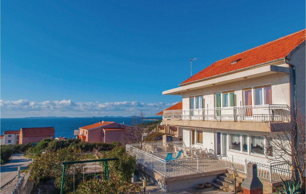 a house with a red roof and the ocean in the background at Stunning Home In Dolac With 5 Bedrooms And Wifi in Primošten