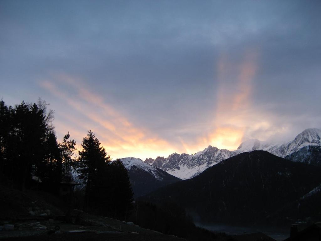 een zonsondergang over de bergen met een regenboog in de lucht bij Mont Blanc Views Apartments in Passy
