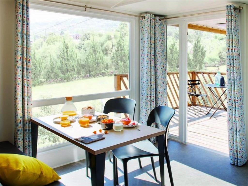 une salle à manger avec une table, des chaises et une grande fenêtre dans l'établissement Mobile home in Sachsenburg Carinthia with pool, à Sachsenburg