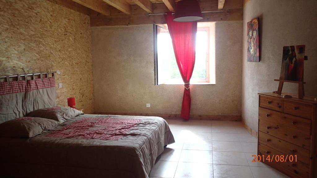 een slaapkamer met een bed en een raam met een rood gordijn bij Au Nid d'hirondelles in Saint-André-de-Chalençon
