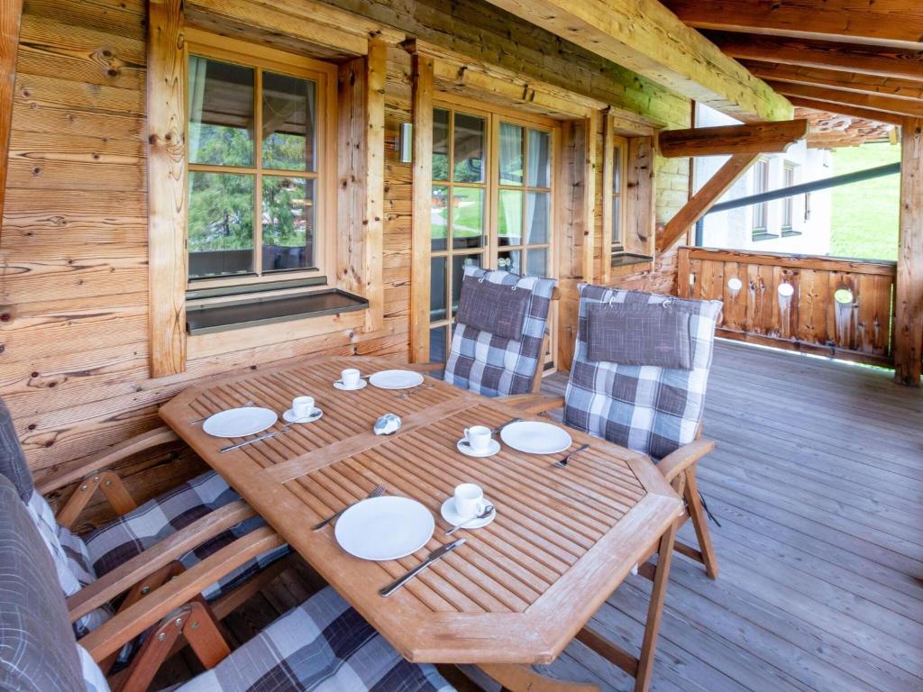 una mesa de madera y sillas en la cubierta de una cabaña en Apartment near the ski area in Mittersill en Hollersbach im Pinzgau