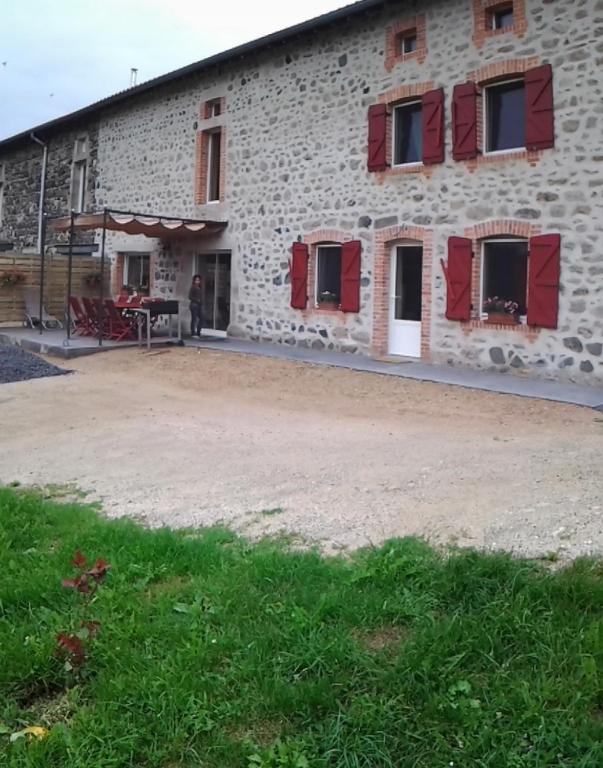 un bâtiment avec des fenêtres à volets rouges et une terrasse dans l'établissement Au Nid d'hirondelles, à Saint-André-de-Chalençon