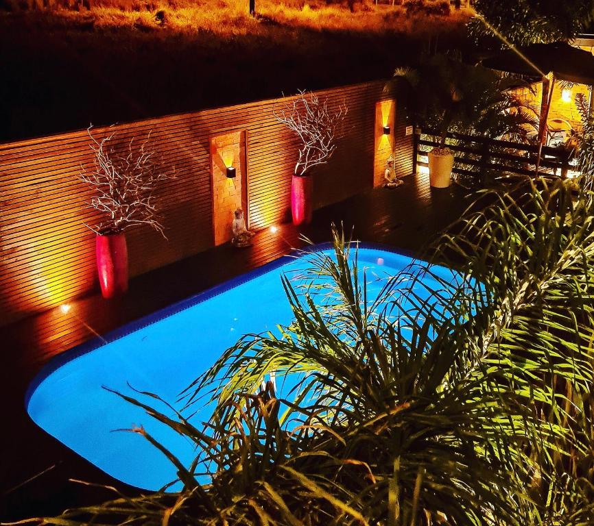 a swimming pool at night with two plants and lights at Pousada Rosa Karioka in Praia do Rosa