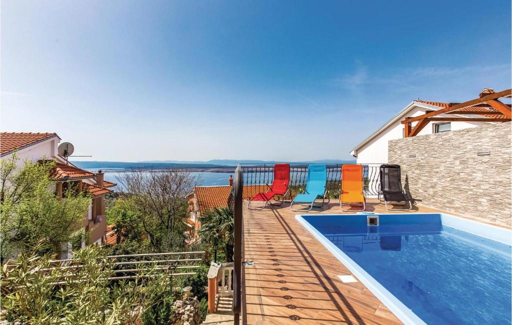 a swimming pool with chairs next to a house at 3 Bedroom Beautiful Apartment In Crikvenica in Crikvenica