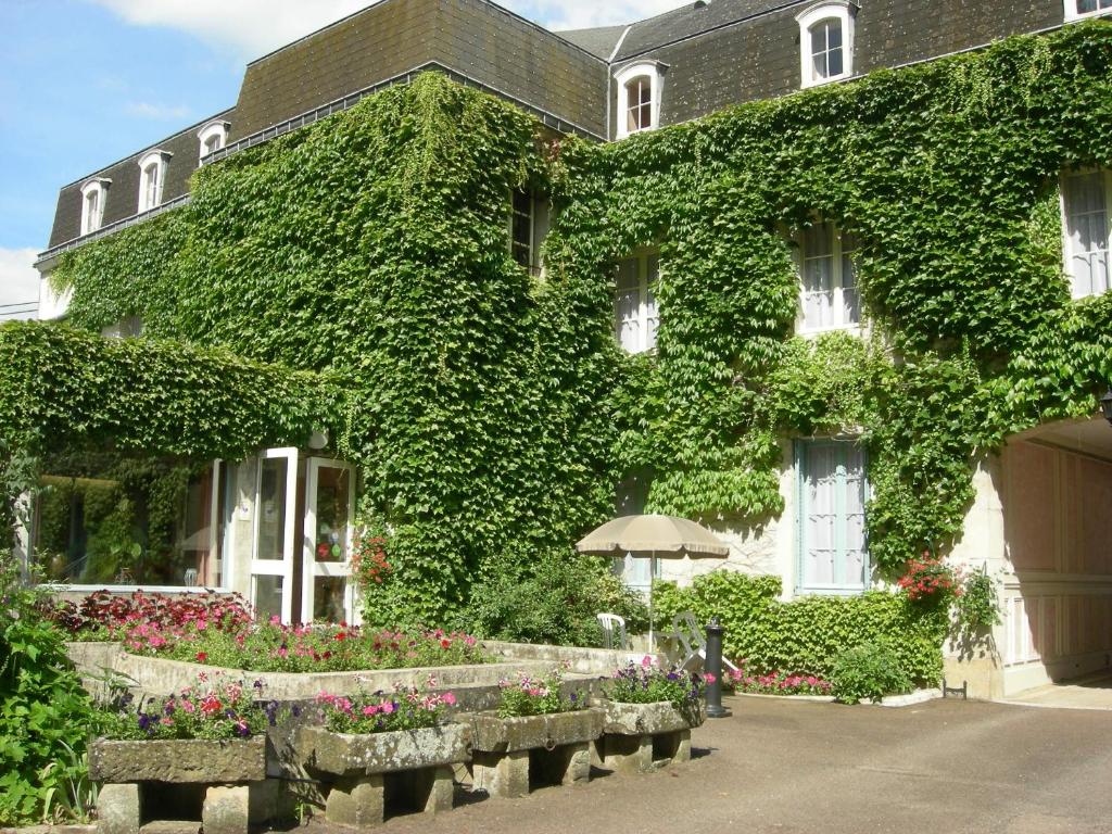 a building covered in ivy with benches in front of it at Cit&#39;Hotel Avallon Vauban in Avallon