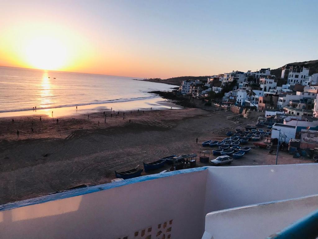 uma vista para a praia ao pôr-do-sol a partir de uma varanda em Single fin beach house em Taghazout