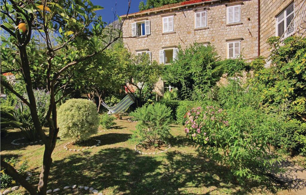 a garden in front of a large brick building at Cozy Home In Zaton Veliki With Kitchen in Trsteno