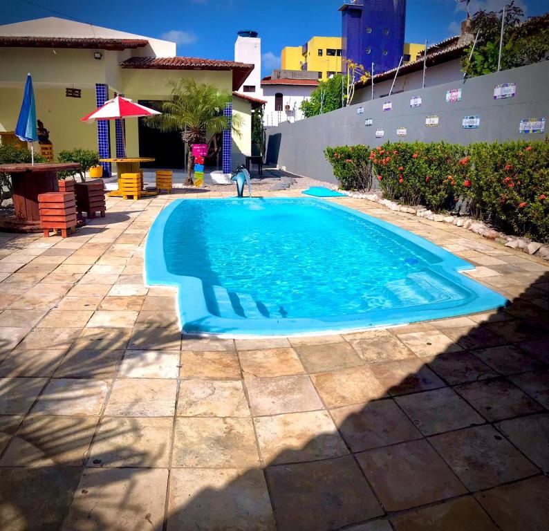a swimming pool with a person standing in the water at Hostel flor do Caribe in Natal