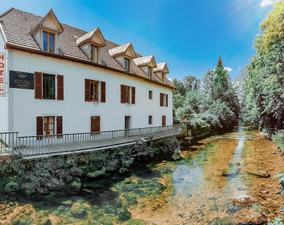 un bâtiment avec une rivière devant lui dans l'établissement Auberge de la Rivière, à Foncine-le-Haut