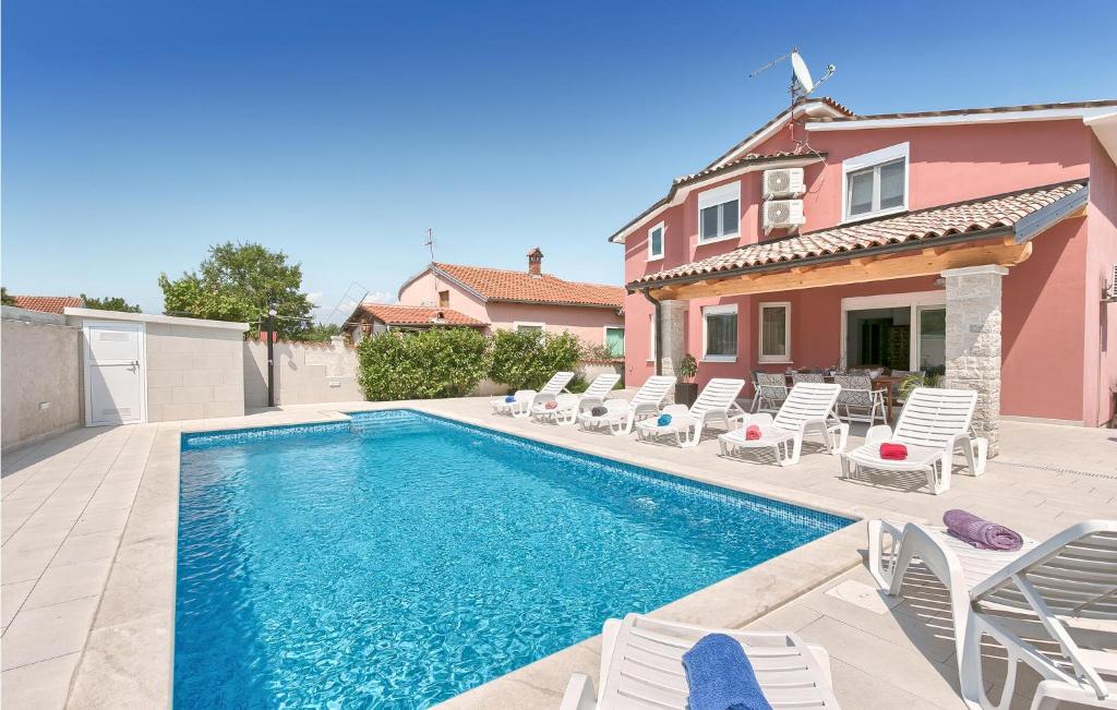 a swimming pool with chairs and a house at Cozy Home In Stinjan With Outdoor Swimming Pool in Štinjan