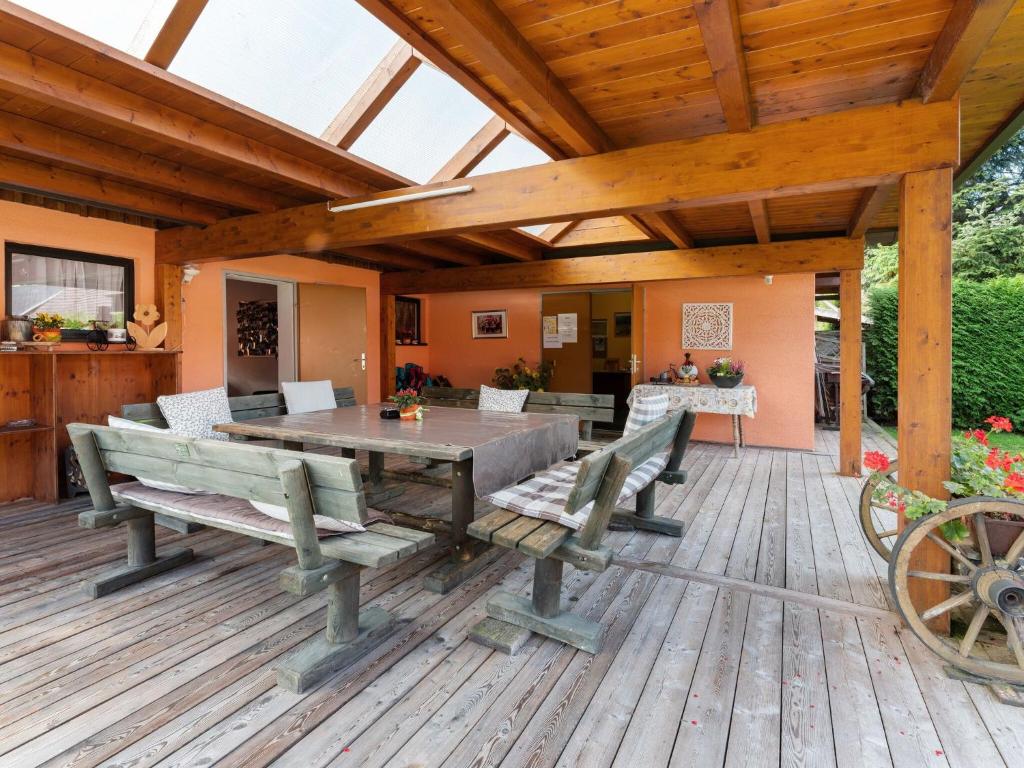 a wooden patio with a table and benches on a deck at Bungalow in Gloednitz in Carinthia with pool in Glödnitz