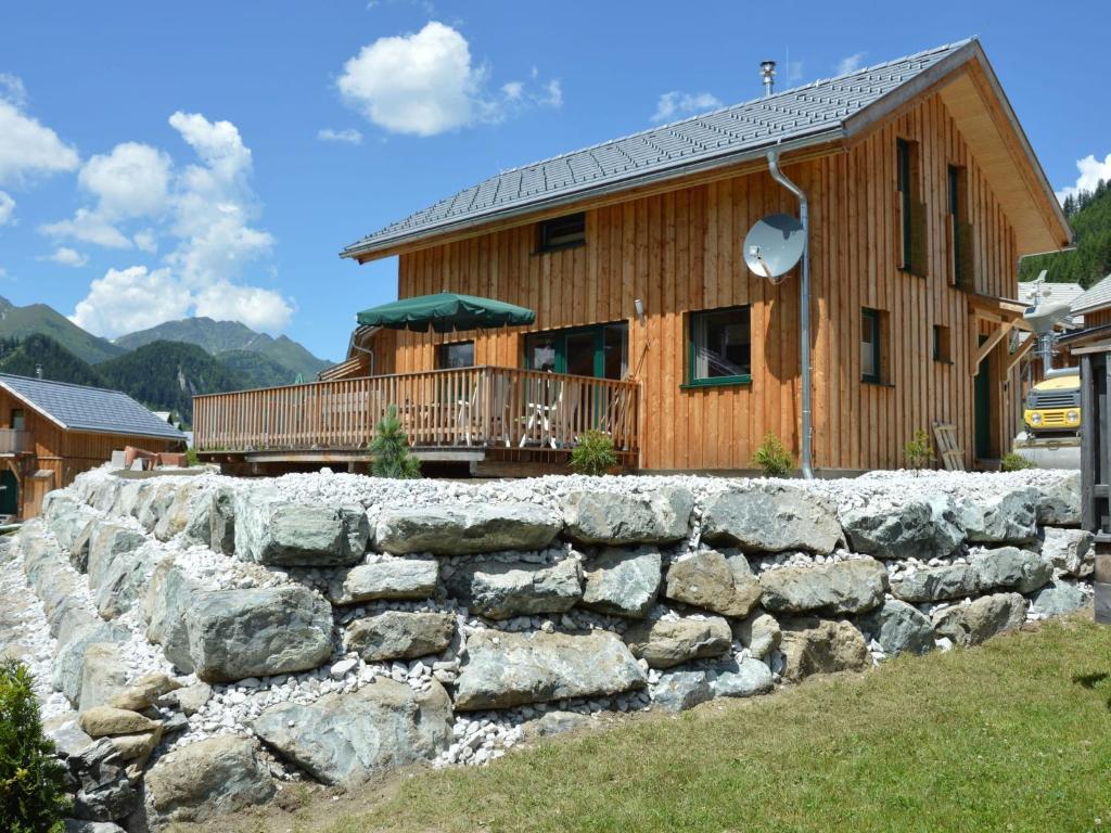 a house with a stone wall in front of a building at Wooden chalet in Hohentauern with sauna in Hohentauern