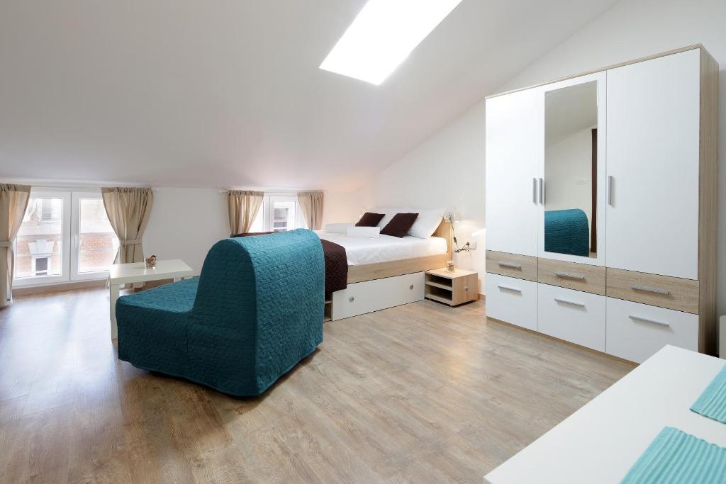 ein Schlafzimmer mit einem Bett, einem Stuhl und einem Spiegel in der Unterkunft Centrally located studio apartment Seagull in Rijeka