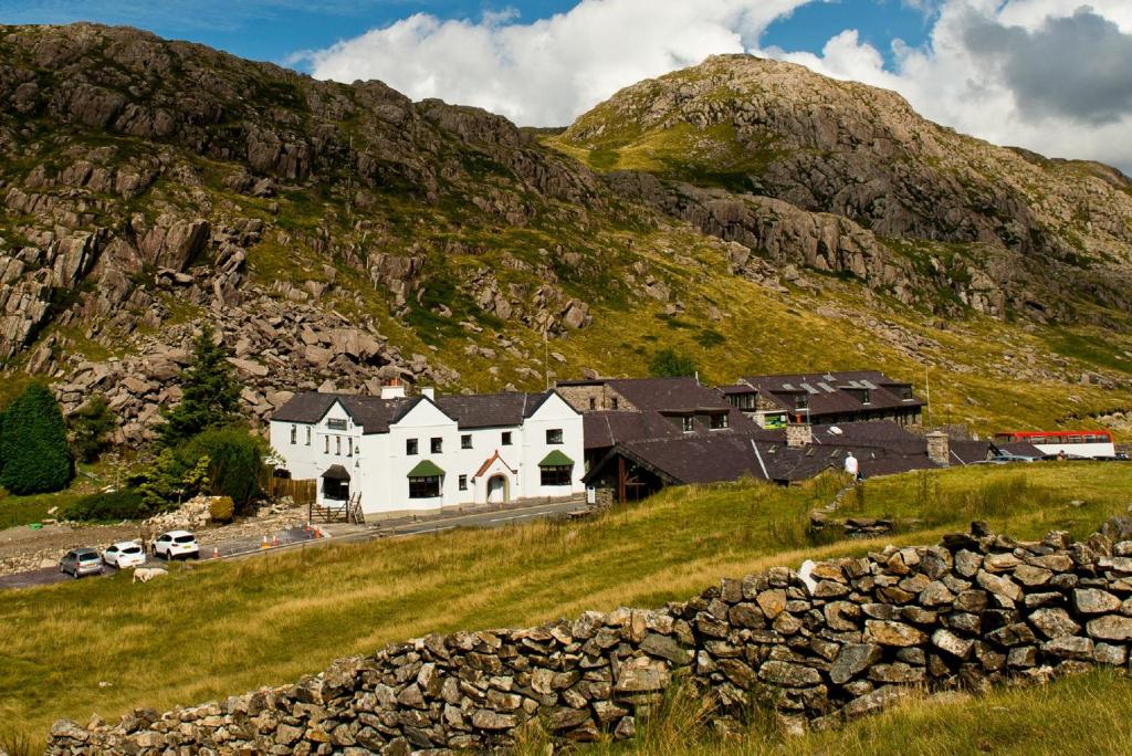 a white building on a hill in front of a mountain at YHA Snowdon Pen-y-Pass in Llanberis