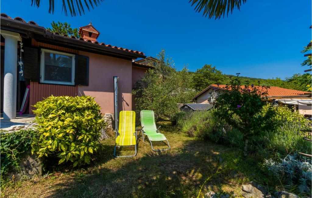 dwa zielone i żółte krzesła na dziedzińcu domu w obiekcie Holiday Home Labin 57 w mieście Drenje
