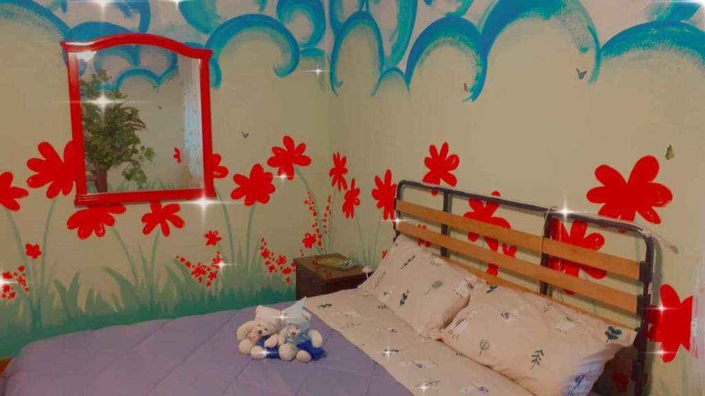 um quarto com uma cama com flores pintadas na parede em Colori nel parco em Cesiomaggiore