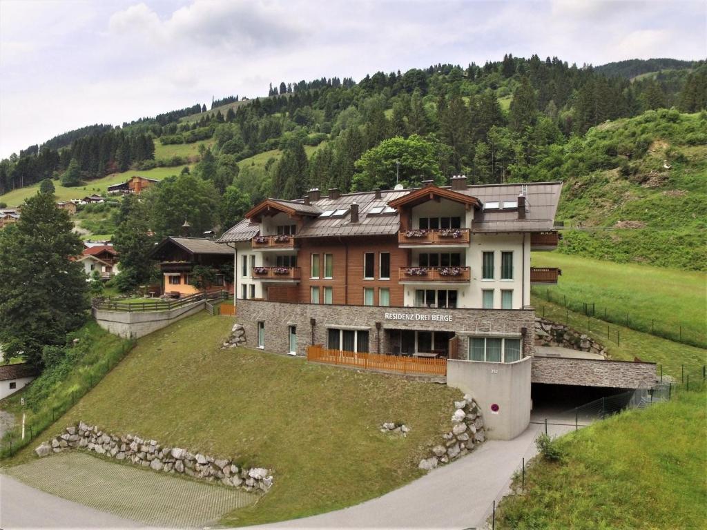 a large house on a hill with a grass yard at Modern Apartment in Saalbach Hinterglemm near Ski Aea in Saalbach-Hinterglemm