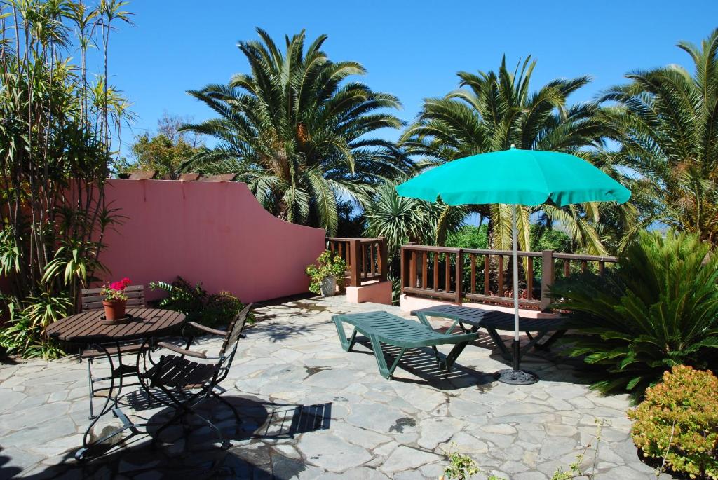 eine Terrasse mit einem Tisch, Stühlen und einem Sonnenschirm in der Unterkunft Casa Bana I in El Paso