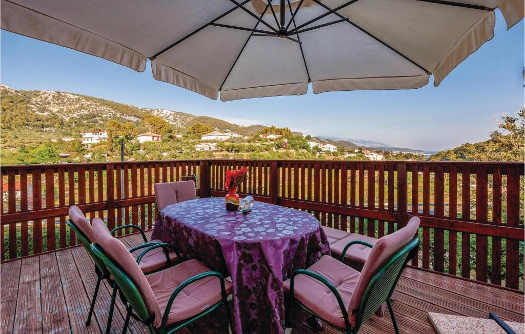 a table with chairs and an umbrella on a deck at Pet Friendly Apartment In Mundanije With House A Panoramic View in Mundanije