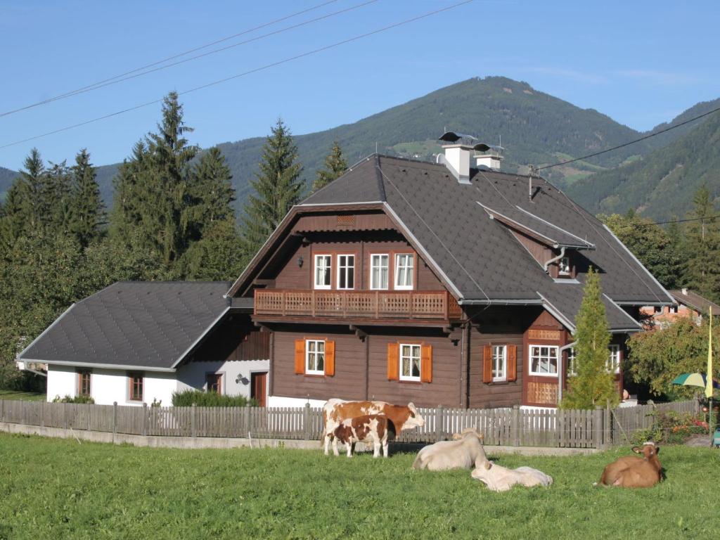 a group of cows laying in the grass in front of a house at Tranquil Holiday Home in Kleblach-Lind with Infrared Sauna in Lind
