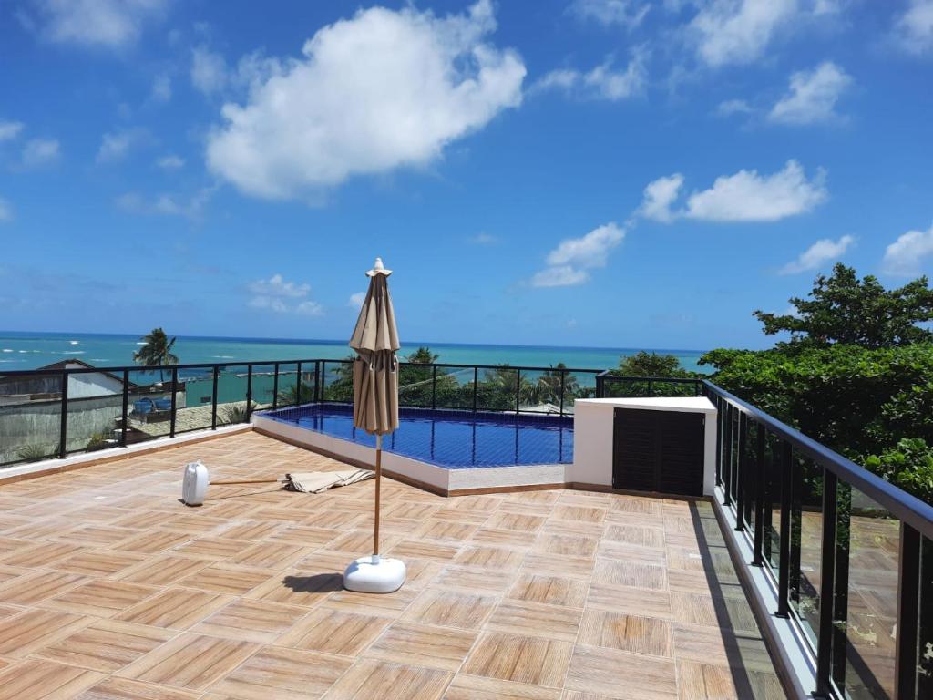 a balcony with an umbrella and a swimming pool at Lindo Flat no Residencial Maraca Beach in Porto De Galinhas