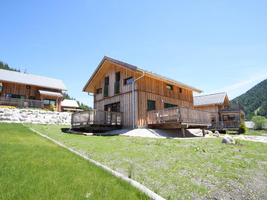 a large wooden house with a grass field in front of it at Chalet in Hohentauern with sauna and hot tub in Hohentauern