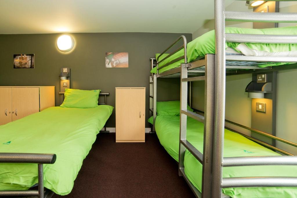 2 łóżka piętrowe w pokoju wieloosobowym z zielonymi łóżkami w obiekcie YHA Berwick w mieście Berwick-upon-Tweed