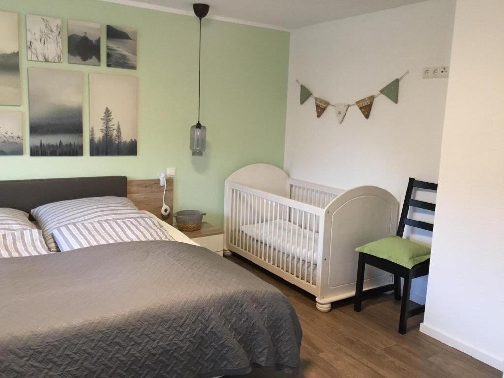 - une chambre avec un lit, un lit bébé et une chaise haute dans l'établissement „Südblick“ gemütliche Doppelhaushälfte, à Lastrup