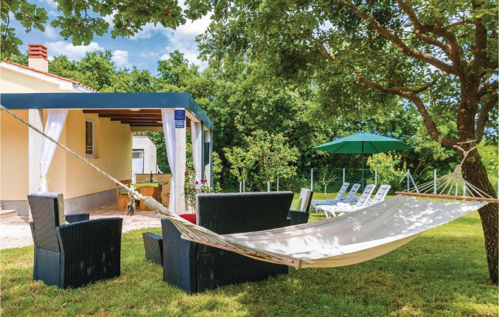 a hammock in a yard with chairs and an umbrella at Beautiful Home In Marcana With Kitchen in Marčana