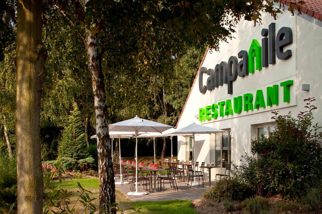 un letrero para un restaurante con mesas y sombrillas en Campanile Valenciennes - Petite-Forêt, en Petite Forêt