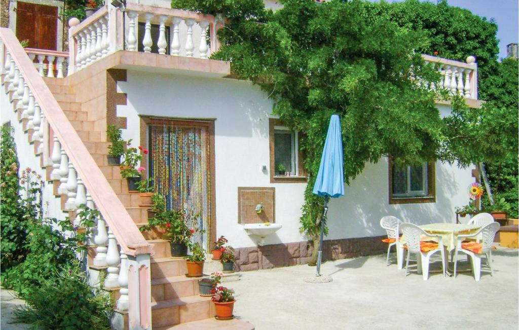 a house with a table and a blue umbrella at Awesome Apartment In Rakalj With House Sea View in Rakalj