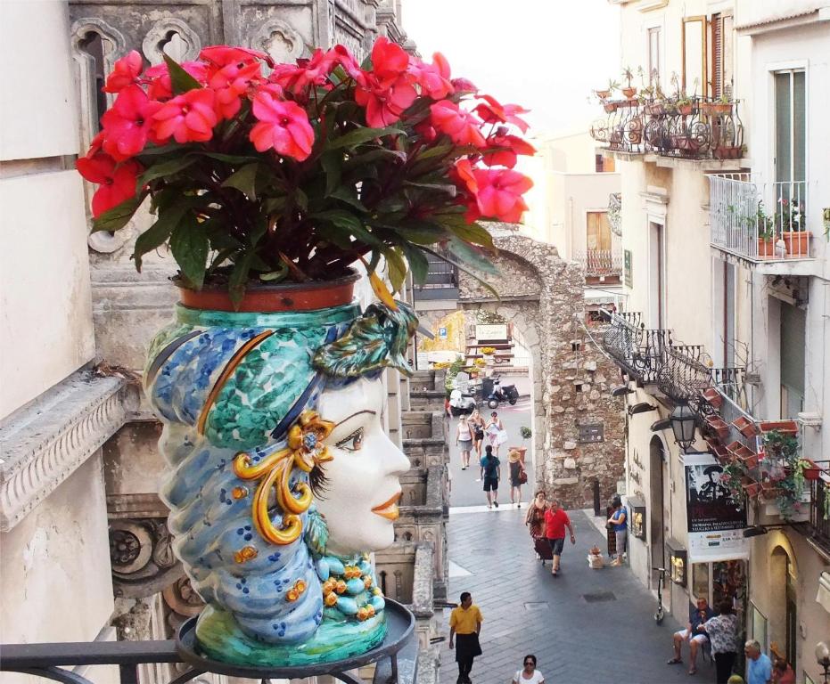 un jarrón lleno de flores en la parte superior de una calle en Valentina en Taormina