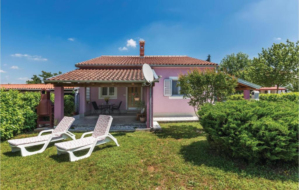 a house with two lawn chairs in the yard at 2 Bedroom Amazing Home In Valbandon in Štinjan