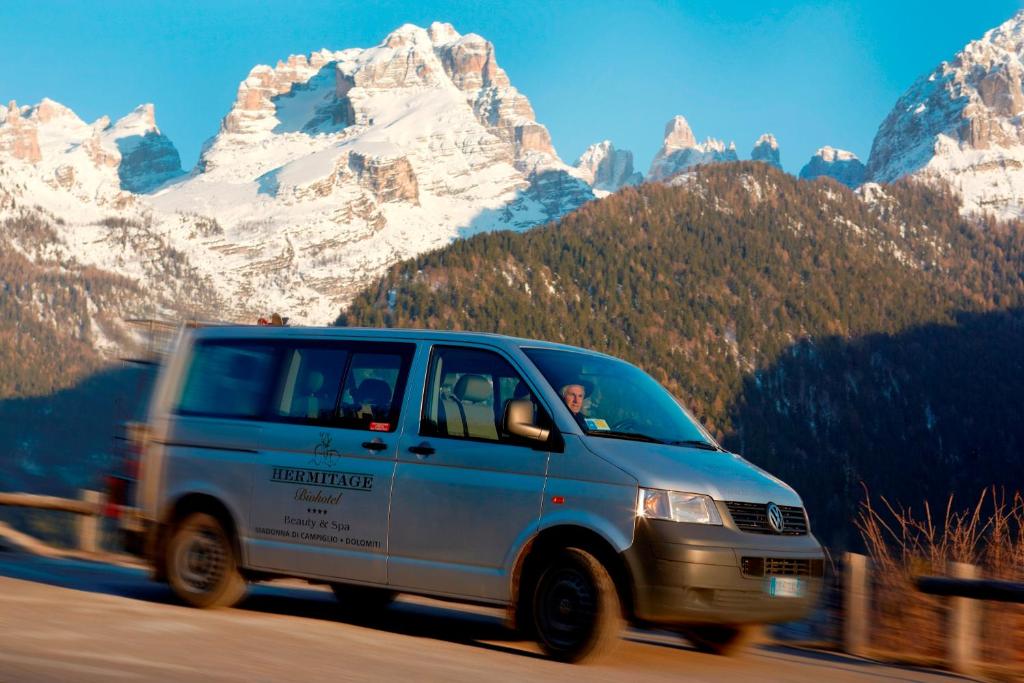 a van driving down a road in front of a mountain at Bio Hotel Hermitage in Madonna di Campiglio
