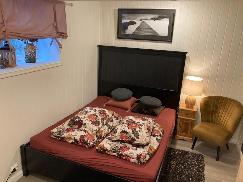 a bedroom with a bed with red sheets and a chair at Downtown Historical House with Renovated apartments in Ålesund