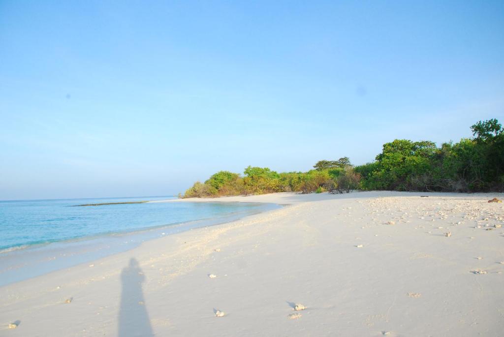 a shadow of a person standing on a beach at PRIV Fodhdhoo in Fodhdhoo